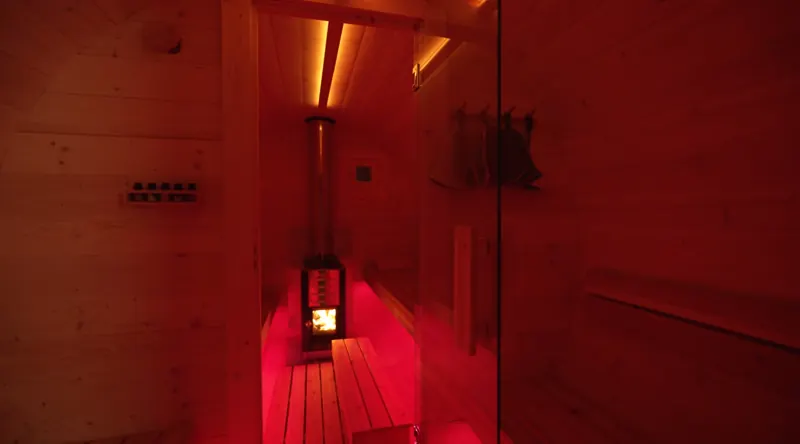 The sauna interior glowing red at night with the stove lit