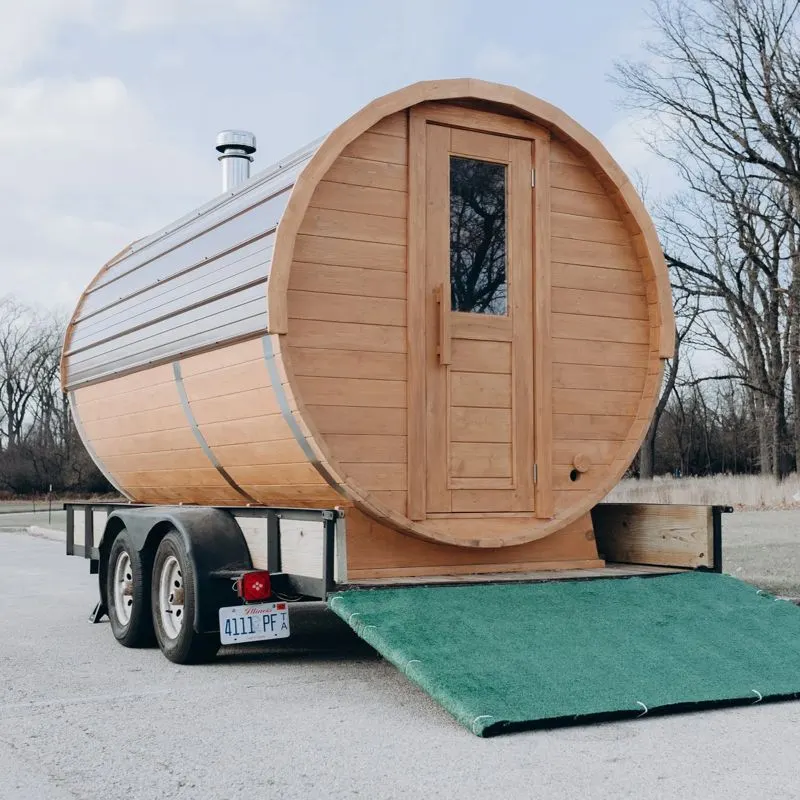 Spruce barrel sauna on its dual-axle trailer with the entry ramp down