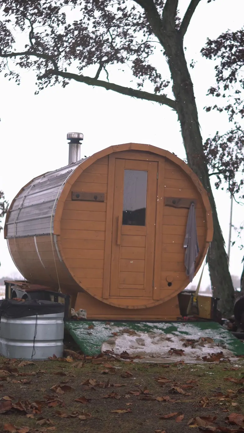 NFinite barrel sauna set up under a tree with a cold plunge tub