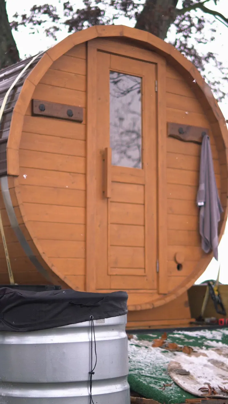 Cold plunge tub beside the sauna door with a towel hanging on the hook